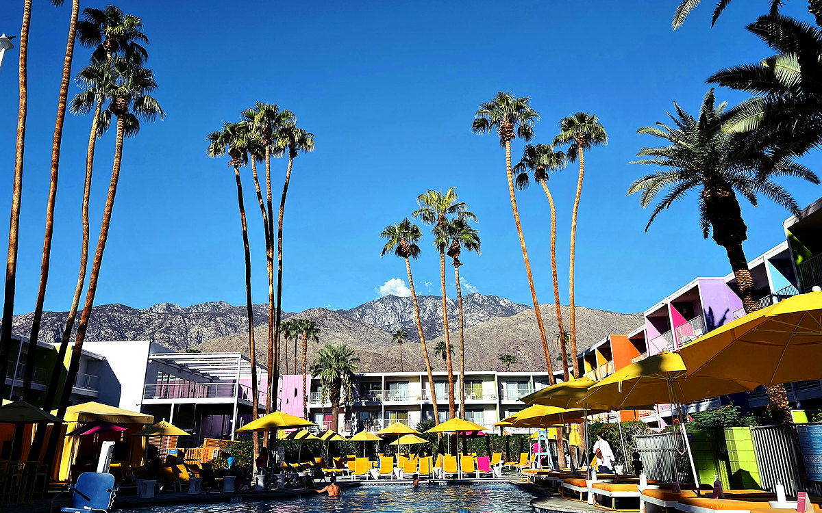 Hotel pool courtyard with palm trees and guest-room balconies in Palm Springs, California