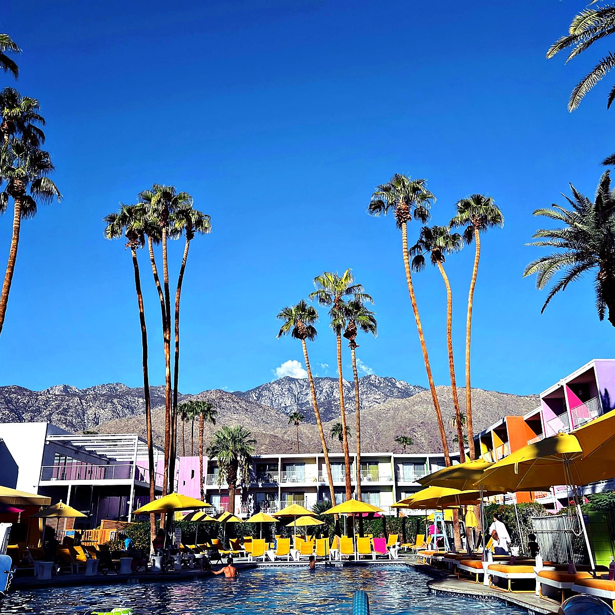 Hotel pool courtyard with palm trees and guest-room balconies in Palm Springs, California