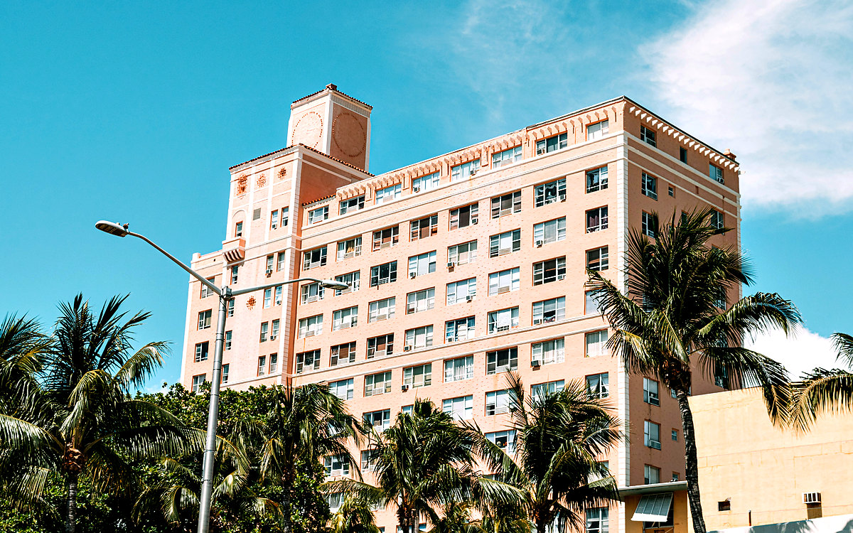 Mid-rise Mediterranean Revival building framed by palm trees, Miami Beach style