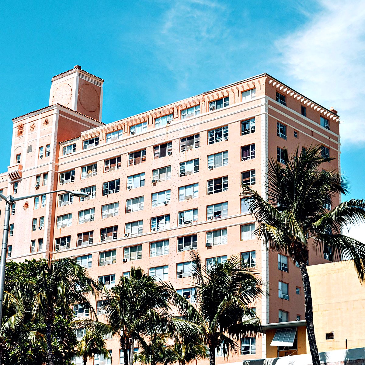 Mid-rise Mediterranean Revival building framed by palm trees, Miami Beach style